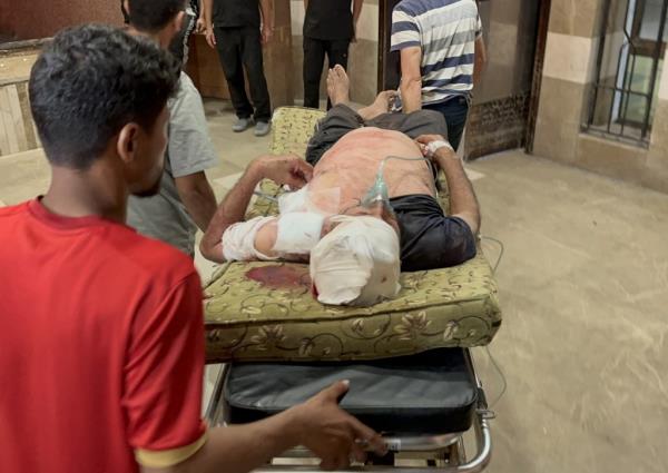 Injured Palestinian on a stretcher being transported to a hospital following an Israeli airstrike on a tent encampment in Khan Yunis, Gaza