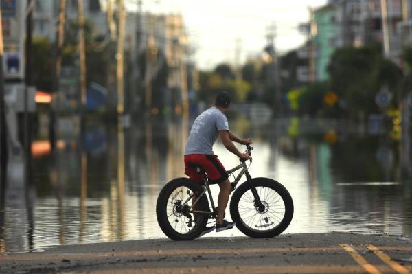 Residents and others look over the standing flood waters 