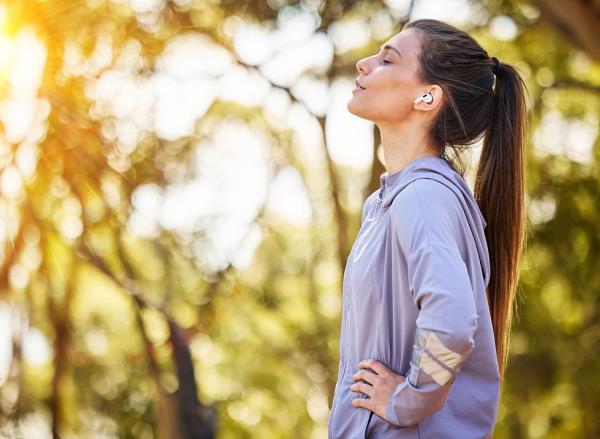 A woman stops to catch her breath while walking outside