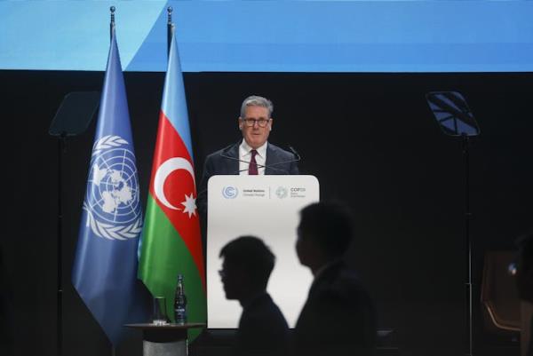 A man in a suit at a podium with UN and Azerbaijani flags next to him.