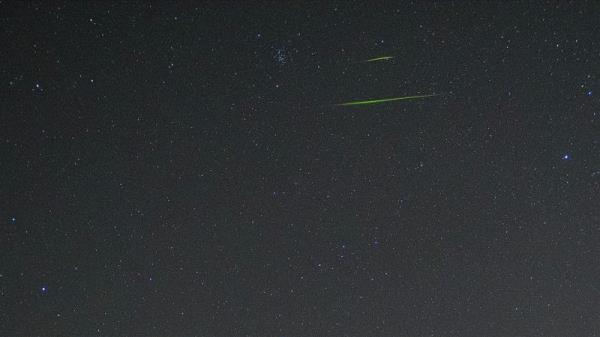 Two thin green horizo<em></em>ntal streaks in dark starry sky.