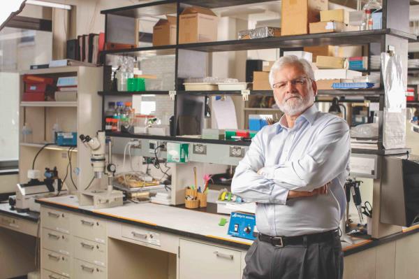 Kerry O'Banion with his arms crossed and looking at the camera while posing for a portrait in his lab.