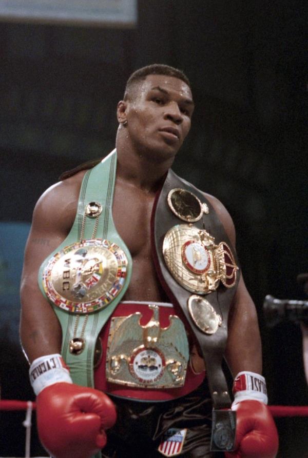 Tyson in the ring with his three heavyweight belts draped over him.