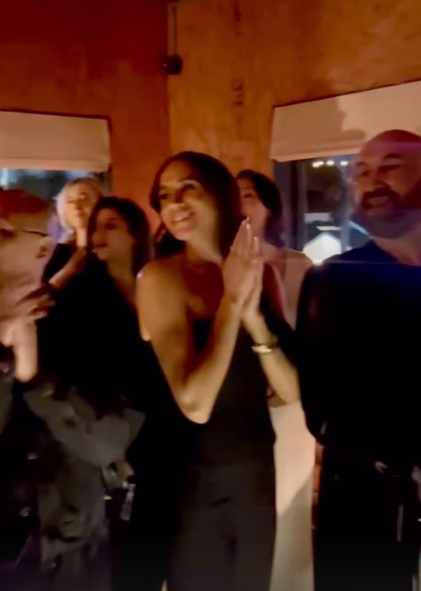 Duchess of Sussex, Meghan Markle, in a black outfit, enjoying a night out with friends and clapping during a brand's launch party in Los Angeles