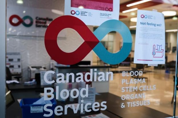 A glass door looking into a blood do<em></em>nation clinic features the Canadian Blood Services logo along with the name and the words blood, plasma, stem cells, organs and tissues.