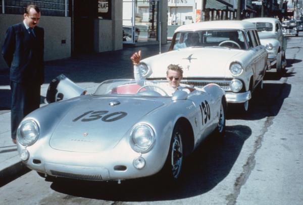 James Dean waves from behind the wheel of his Porsche 550 Spyder 'Little Bastard' parked on Vine Street in Los Angeles, California.