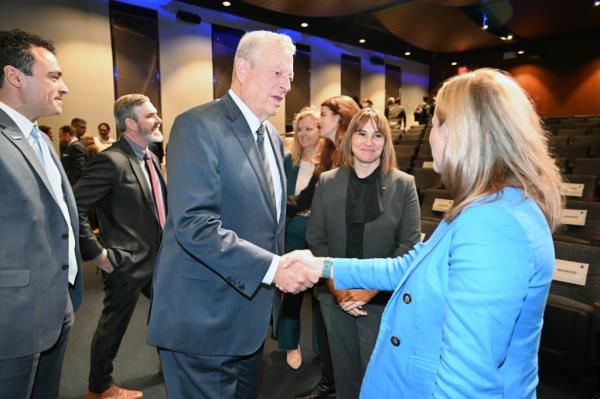 Al Gore (left) in a business suit, shakes hands with Dalia B. Kirschbaum, director of NASA Goddard's Earth Sciences Division. Goddard Center Director Makenzie Lystrup looks on from between them. Miguel Román, Goddard Earth Sciences Division's deputy director for atmospheres, looks on from far left.